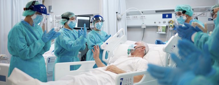 Healthcare professionals clapping for a recovered COVID patient